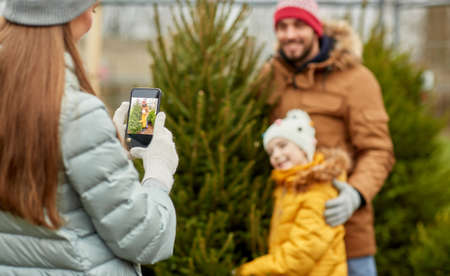 family taking picture of christmas tree at marketの写真素材