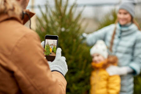 family taking picture of christmas tree at marketの写真素材