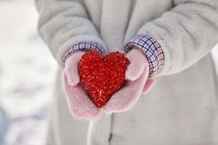 close up of little girl holding heart in winterの写真素材