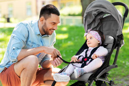 happy father with child in stroller at summer parkの写真素材
