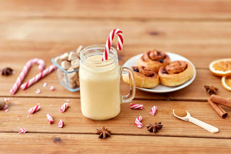 eggnog with candy cane in mug and cinnamon bunsの写真素材