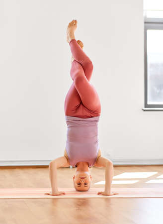 woman doing supported headstand at yoga studio