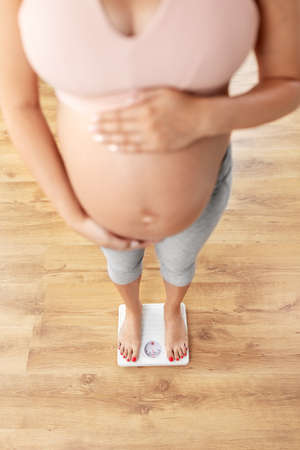 pregnant woman standing on scales at homeの写真素材