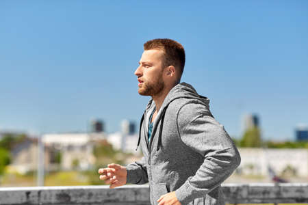 happy young man running across city bridge