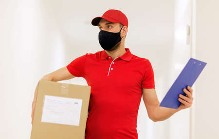 delivery man in mask with box and clipboardの写真素材