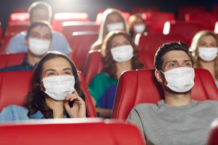 people in masks watching movie in theater