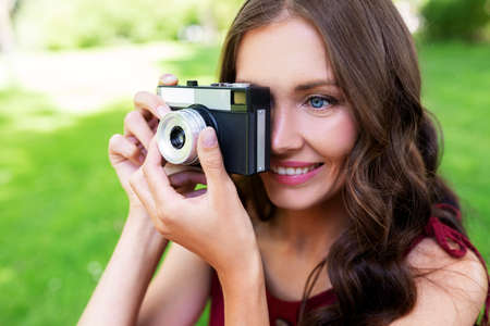 happy woman with camera photographing at park