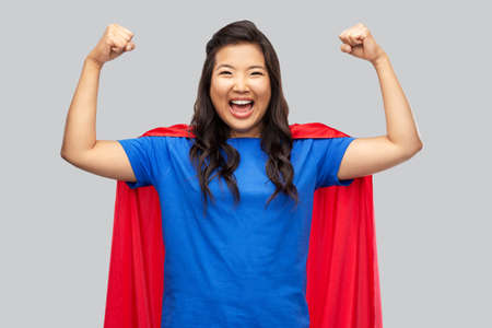 happy asian woman in red superhero capeの写真素材