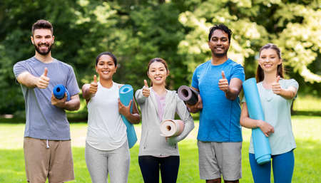 people with yoga mats showing thumbs up at park
