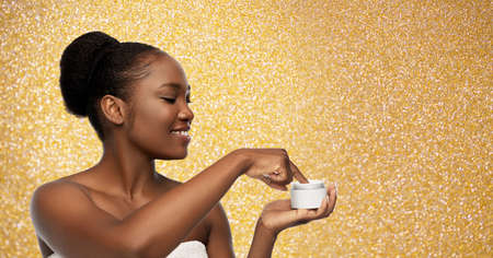 smiling african american woman with moisturizer