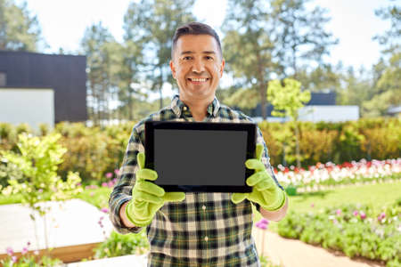 happy middle-aged man showing tablet pc at gardenの写真素材