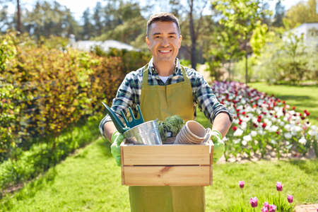 happy man with tools in box at summer garden