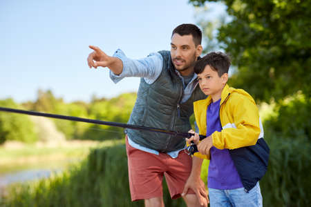 happy smiling father and son fishing on riverの写真素材