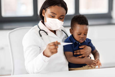 doctor in mask measuring babys temperature
