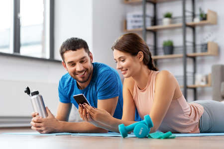 happy couple with smartphone after sports at home