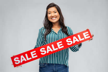 happy smiling young asian woman with sale bannerの写真素材