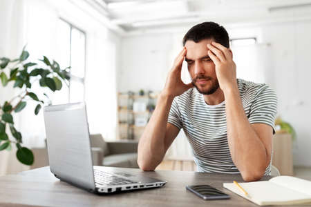 stressed man with laptop working at home office