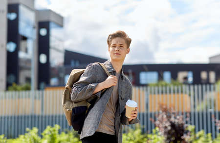 young man with backpack drinking coffee in city