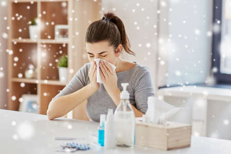 sick woman with medicine blowing nose to wipe
