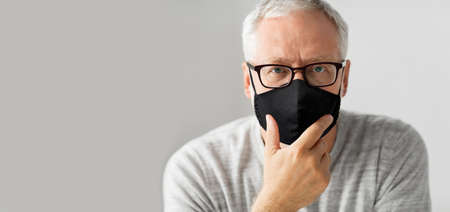 close up of senior man in glasses and black mask