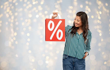 asian woman with percentage sign on shopping bagsの写真素材
