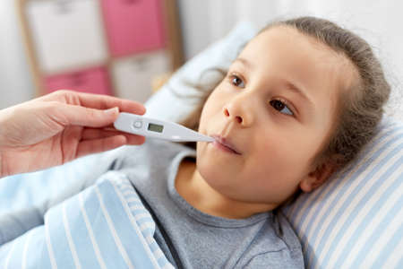 mother and sick daughter measuring temperature