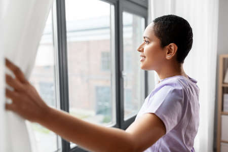 happy african american woman looking out of windowの写真素材