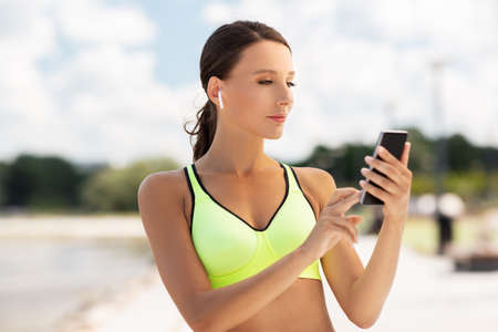 woman with earphones and smartphone doing sports