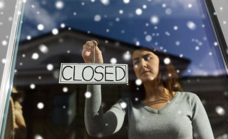 woman hanging banner with closed word on door