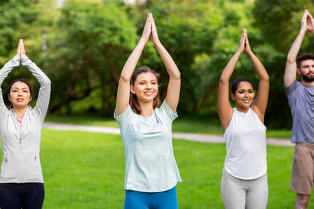 group of people doing yoga at summer parkの写真素材