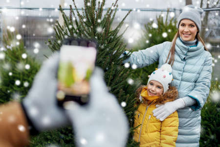 family taking picture of christmas tree at marketの写真素材