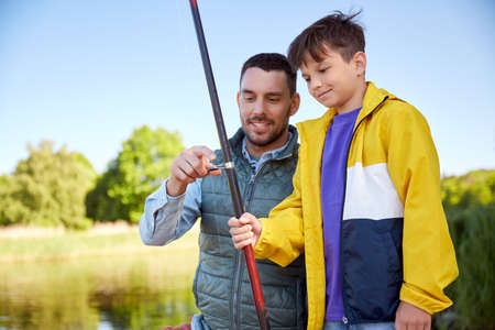 happy smiling father and son fishing on riverの写真素材