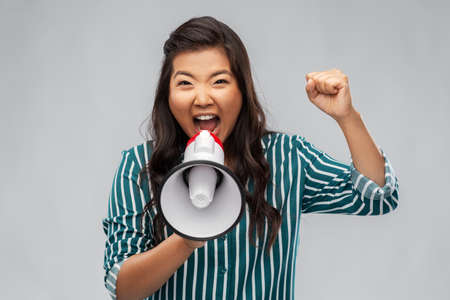 angry young asian woman speaking to megaphoneの写真素材