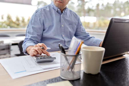 man with calculator and papers working at homeの写真素材