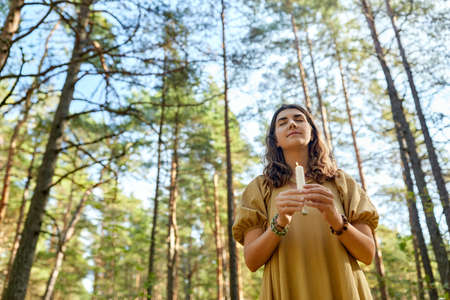 woman or witch performing magic ritual in forest