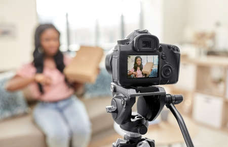 female video blogger with camera and box at home