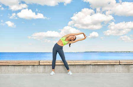 young woman doing sports and stretching outdoors