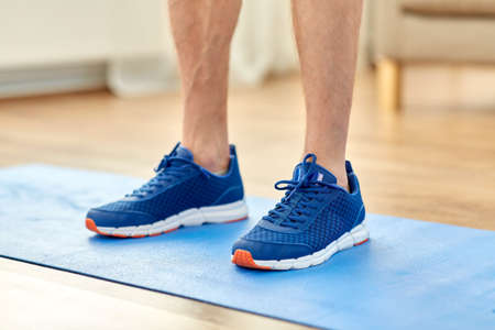 close up of male feet in sneakers on exercise mat