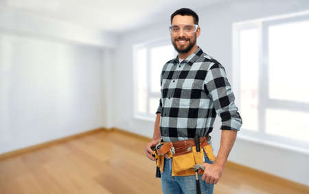 happy male worker or builder with tool beltの写真素材