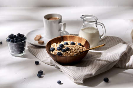 oatmeal with blueberries, milk and cup of coffeeの写真素材