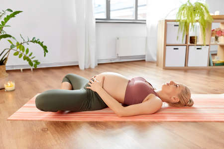 happy pregnant woman doing yoga at home