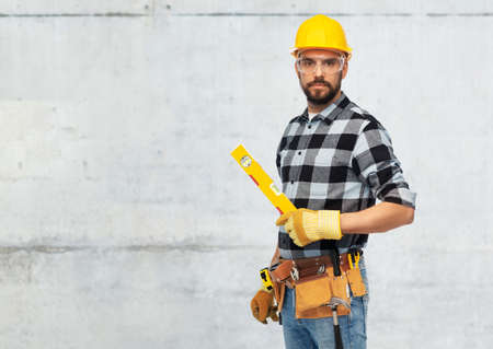 male worker or builder in helmet with level