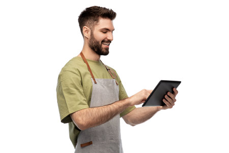 smiling waiter in apron with tablet pc computerの写真素材