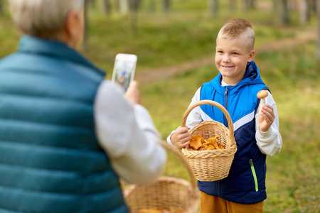 grandmother photographing grandson with mushroomsの写真素材