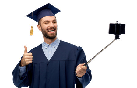 male graduate student with smartphone takes selfieの写真素材