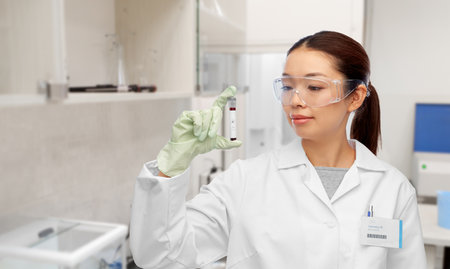 asian female doctor holding beaker with blood test
