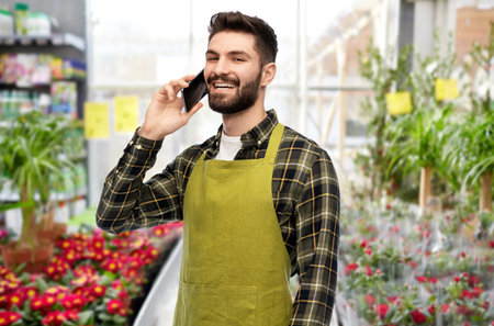 male gardener calling on smartphone at flower shopの写真素材