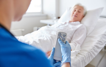 nurse adjusting bed for senior woman at hospitalの写真素材