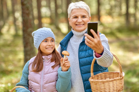 grandma with granddaughter taking selfie in forestの写真素材