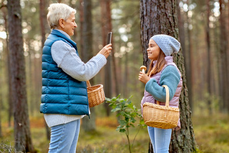 grandma photographing granddaughter with mushroomsの写真素材